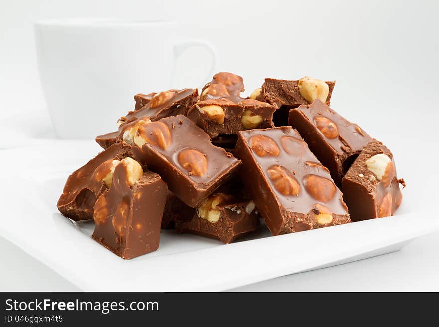 Broken chocolate pieces with nuts on white plate