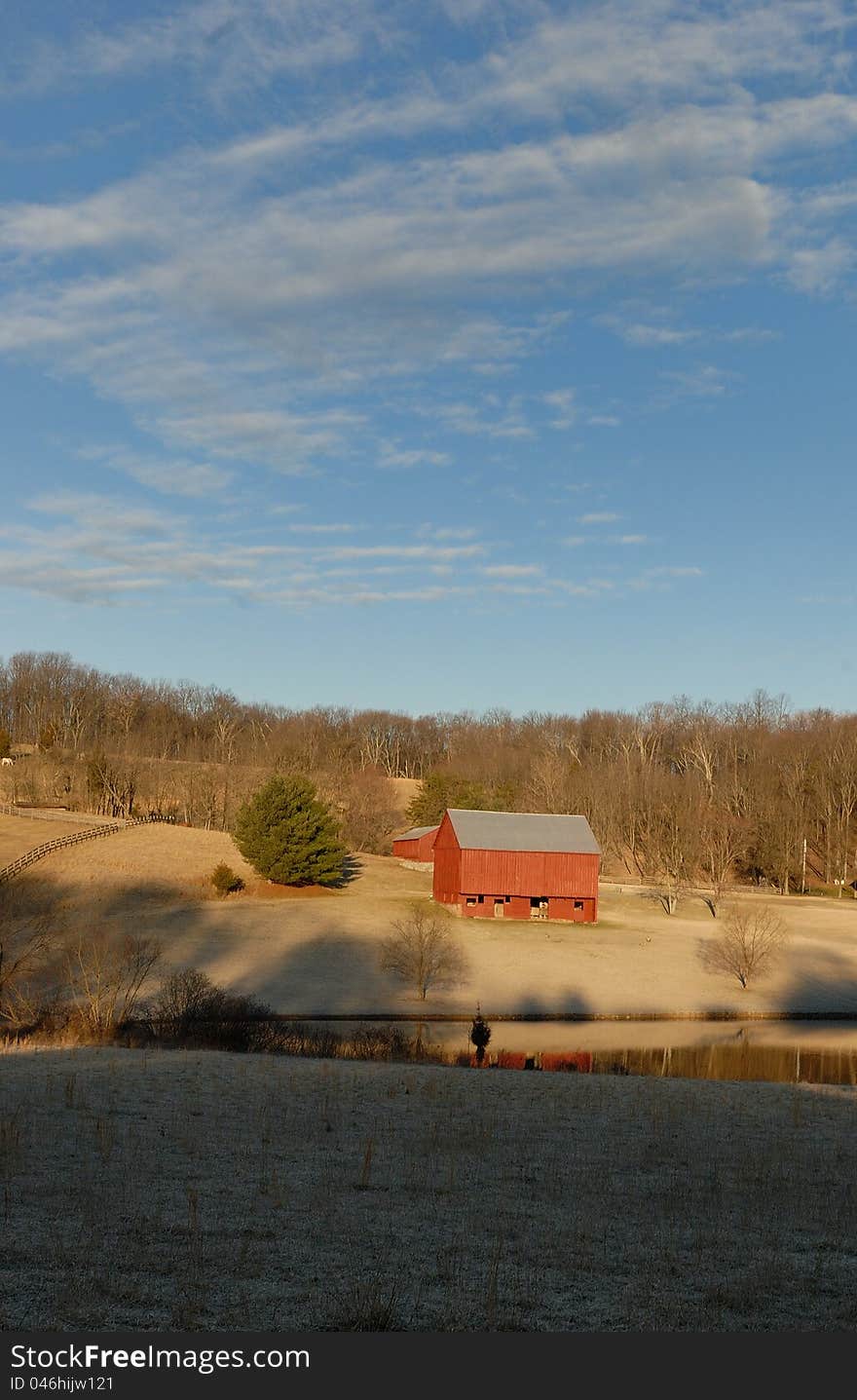 Red barn in morning light with pond in foreground