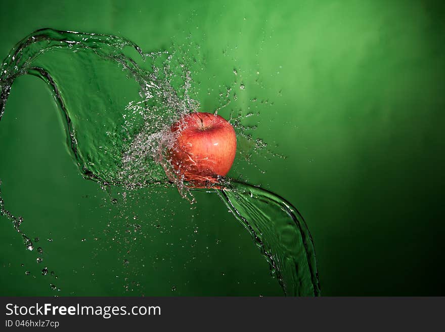 Apple splashed with water on a green background