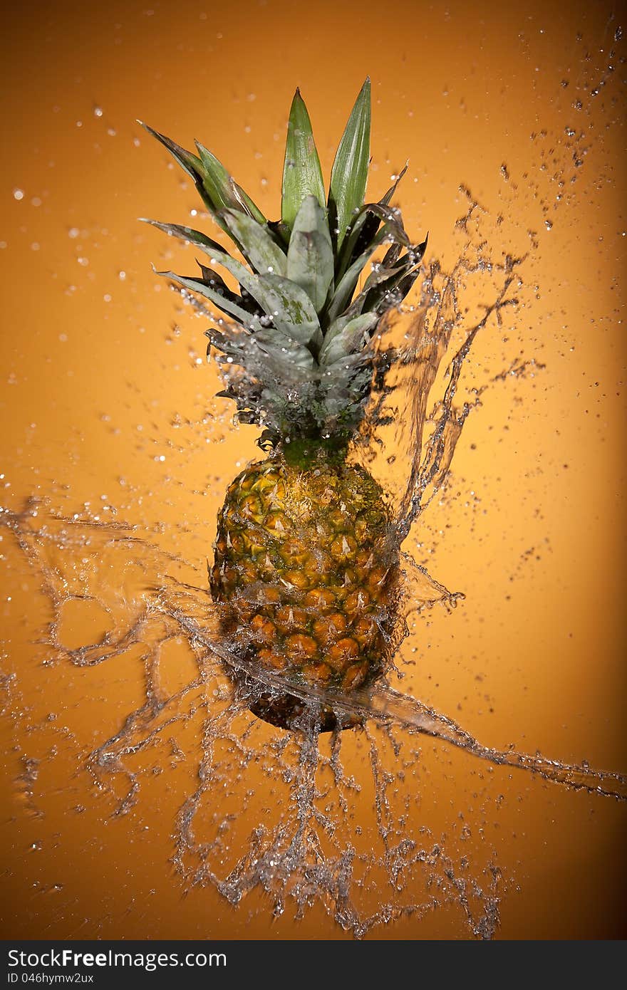 Pineapple splashed with water on a yellow background