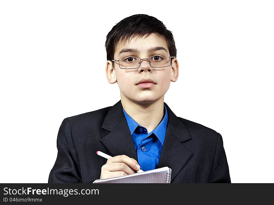 A boy with glasses writes in a notebook