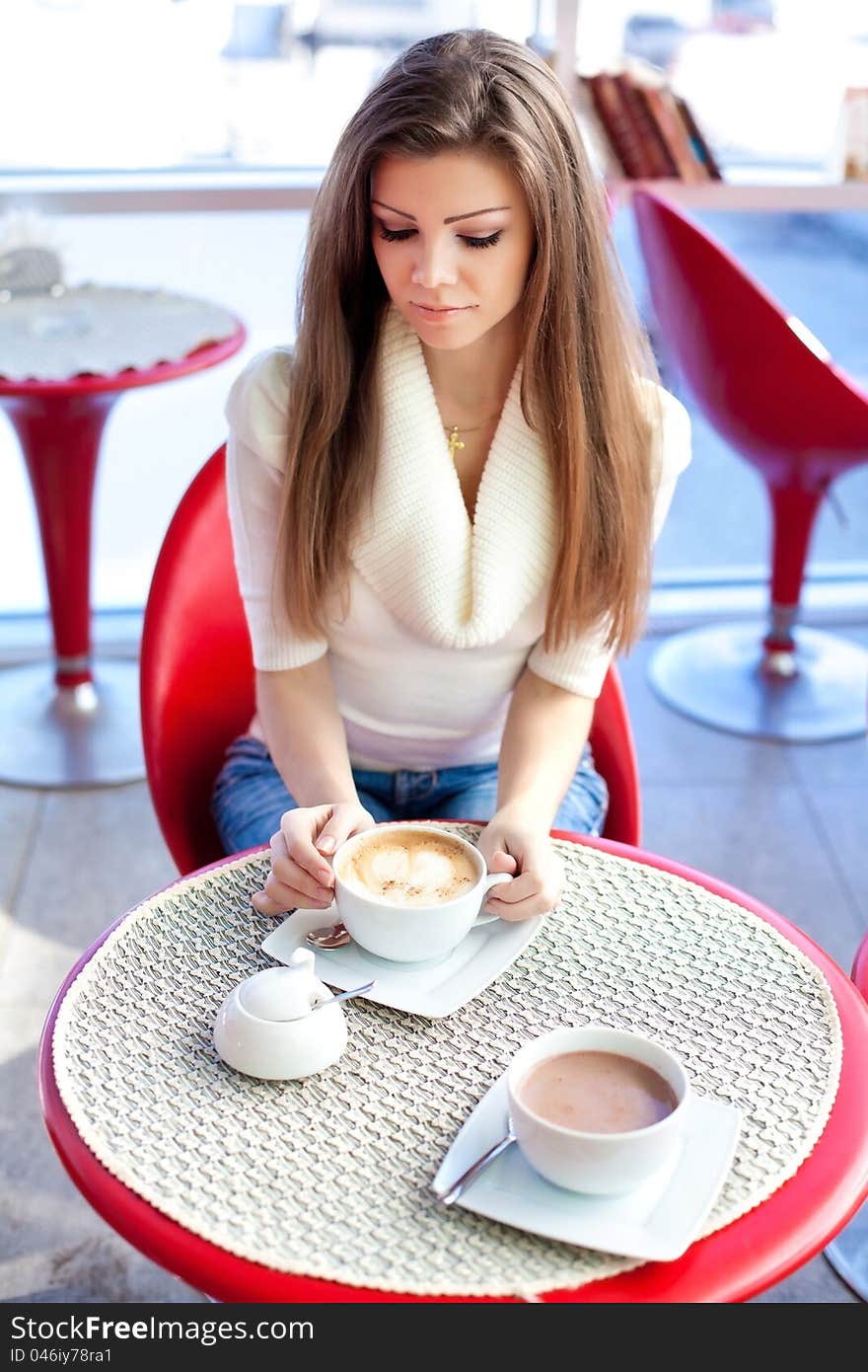 Pretty young woman sitting in the cafe with a cup. Pretty young woman sitting in the cafe with a cup