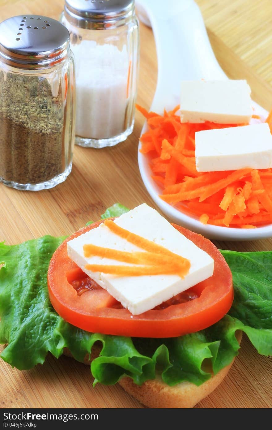 Healthy snack; carrots with soy tofu, sandwich with tomato, salad and tofu on white bread.