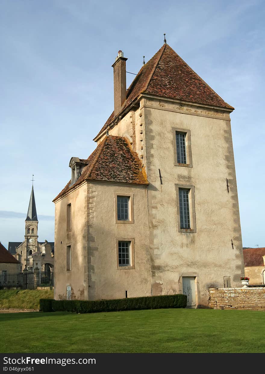 The chateau de Commarin (castle) is located in Burgundy, France. This is a secondary building on the property, with the church in the background.