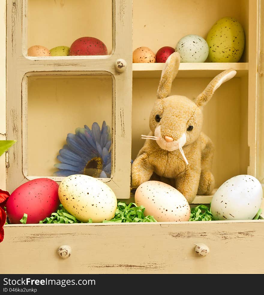 A stuffed Easter bunny in a cupboard full of speckled Easter eggs. A stuffed Easter bunny in a cupboard full of speckled Easter eggs.