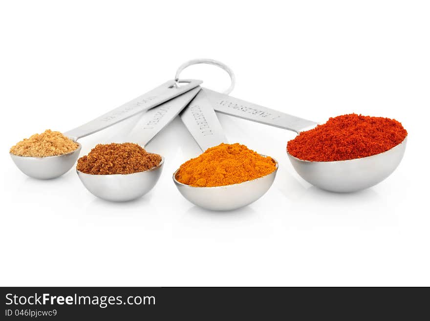 Spice selection of ground ginger, mace, turmeric and cayenne pepper in measuring spoons over white background. Spice selection of ground ginger, mace, turmeric and cayenne pepper in measuring spoons over white background.