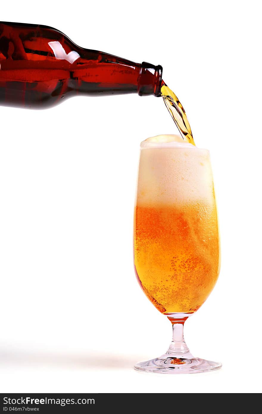 Beer pouring from bottle into glass on white background