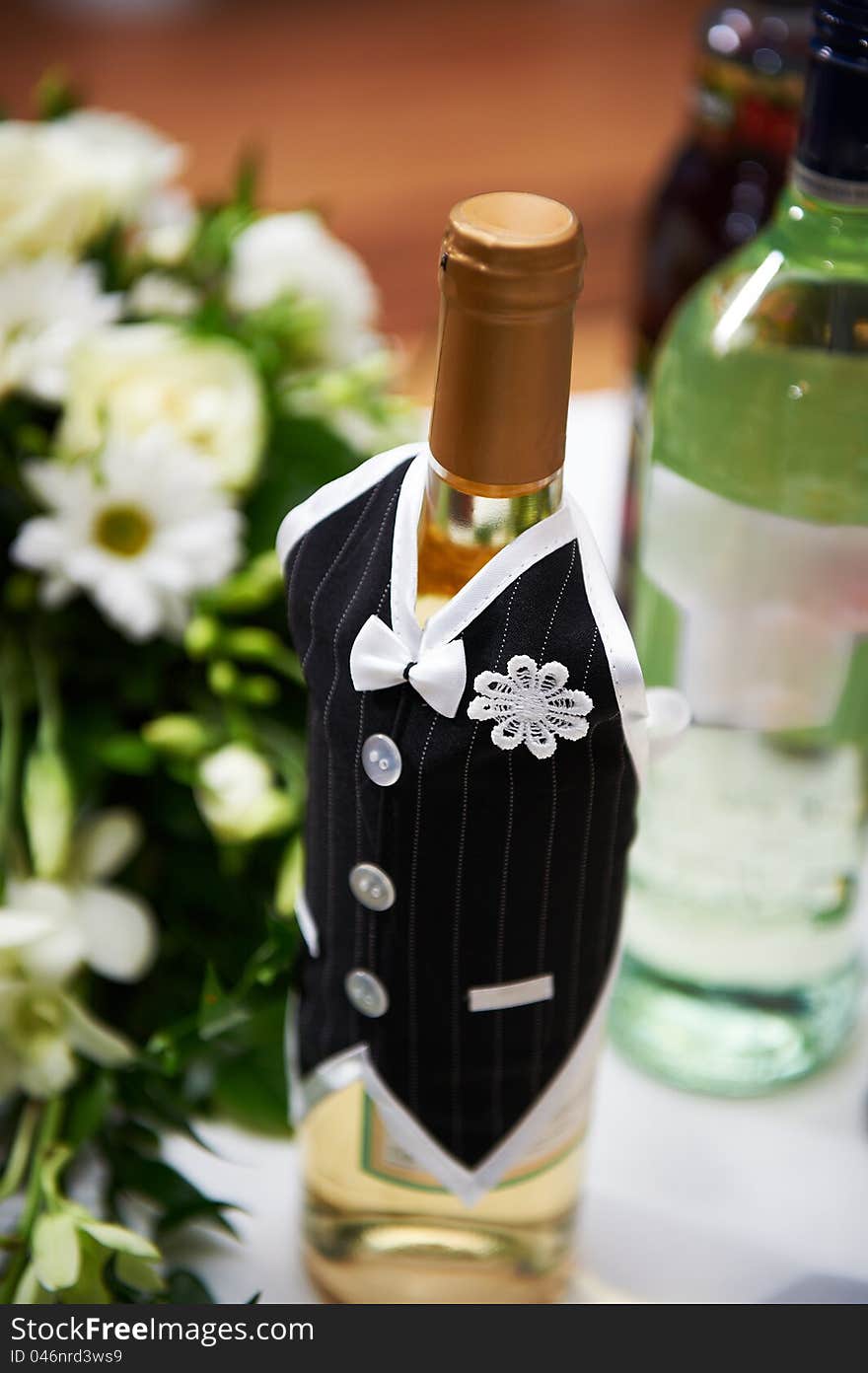 Bottle of vine in the costumes of groom on wedding table