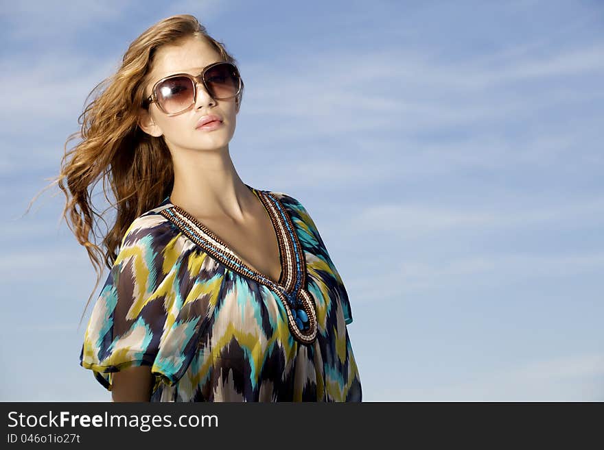 Beautiful girl in sunglasses on blue sky