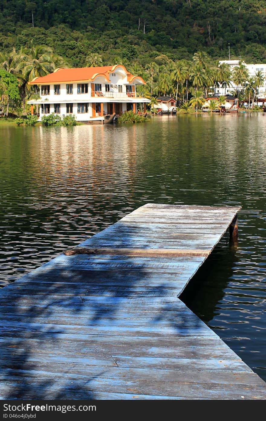 Pier on lake in background with villa and tropical landscape