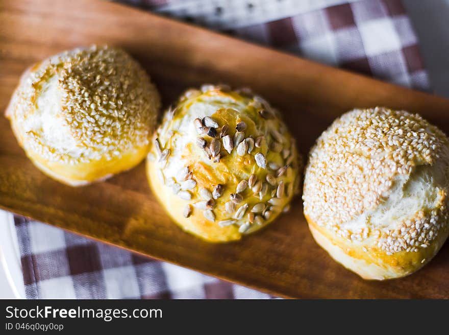 Three buns with seeds on wood plate closeup