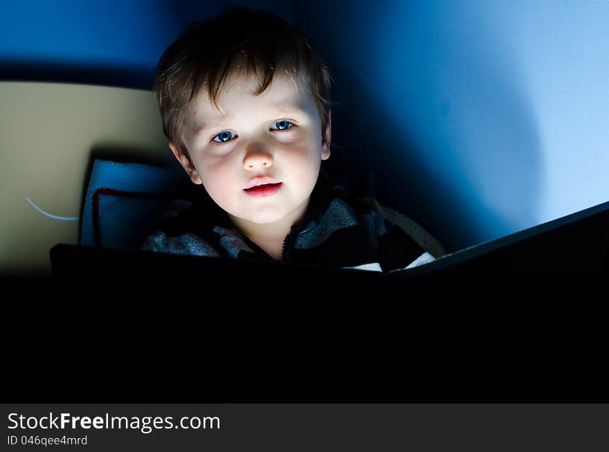 Little boy reading a book in his bed at night. Little boy reading a book in his bed at night