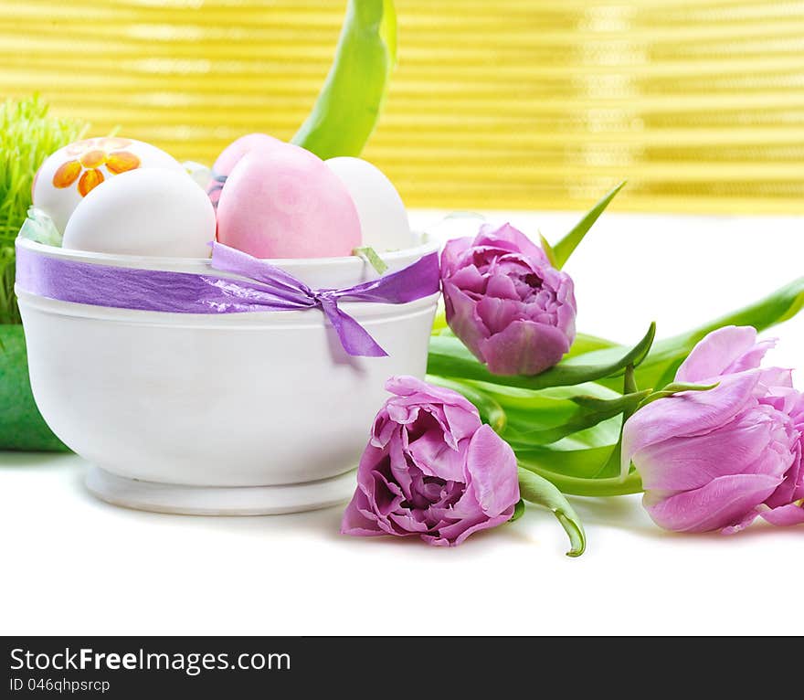 Colorful easter eggs in basket with pink tulips