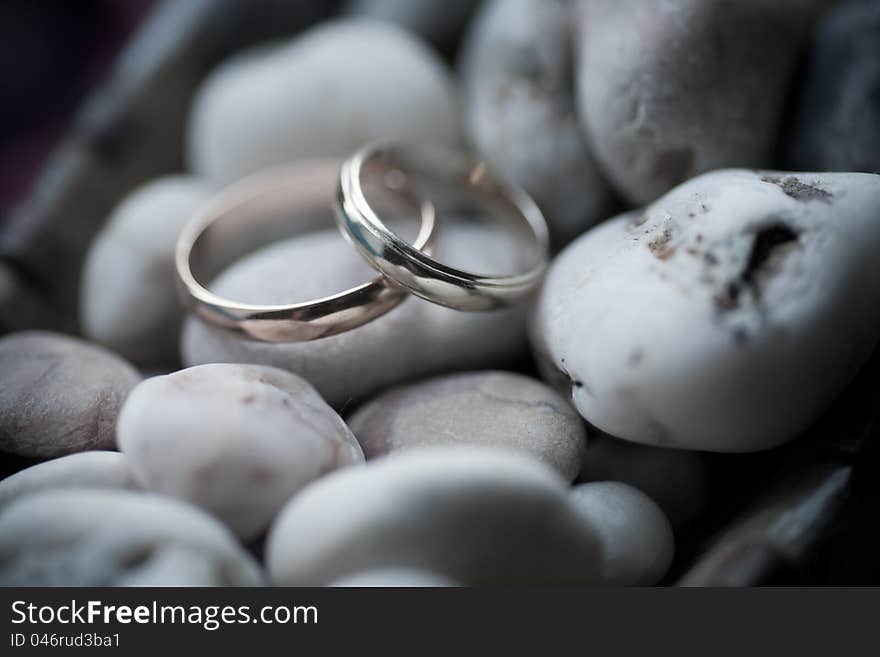 Wedding rings on sea stone background