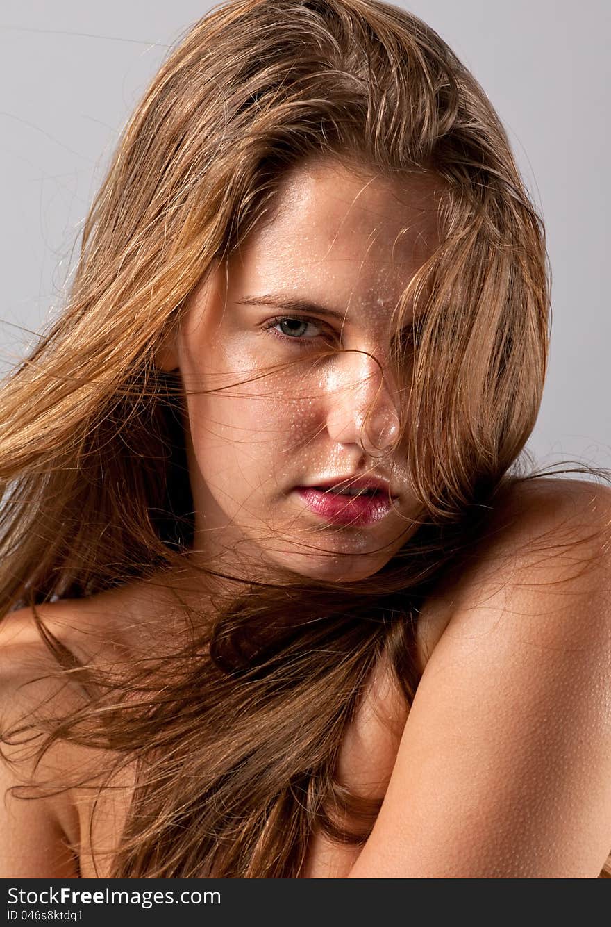 A fun image of a gorgeous young women with wet hair and face, with her hair blowing across her face. A fun image of a gorgeous young women with wet hair and face, with her hair blowing across her face