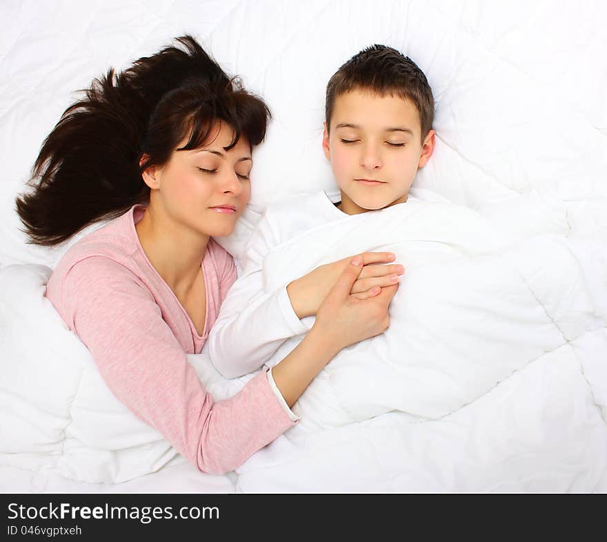 Mother holding her son`s hand , sleeping covered with white blanket. Mother holding her son`s hand , sleeping covered with white blanket