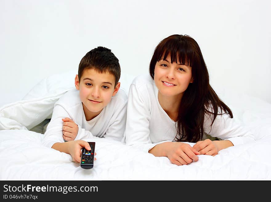 Mother and son lie in bed with remote control