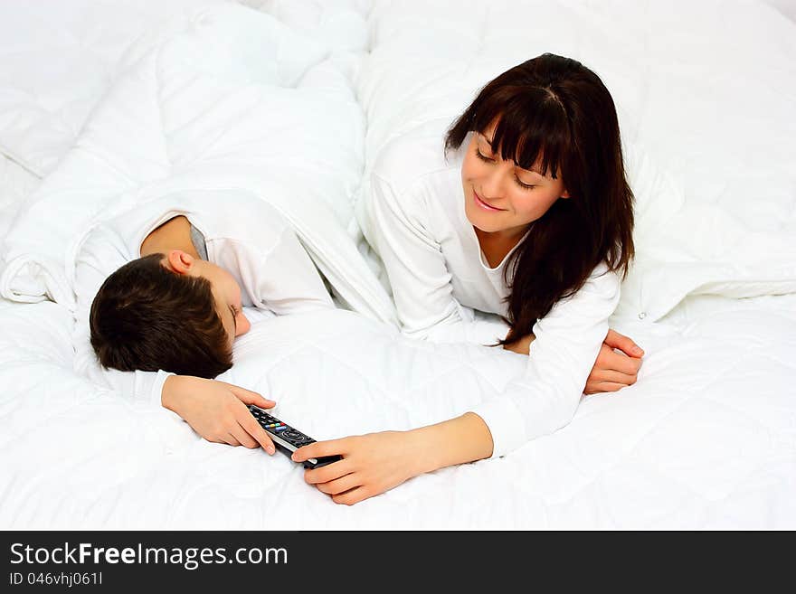 Mother taking a remote control from her sleeping son. Mother taking a remote control from her sleeping son