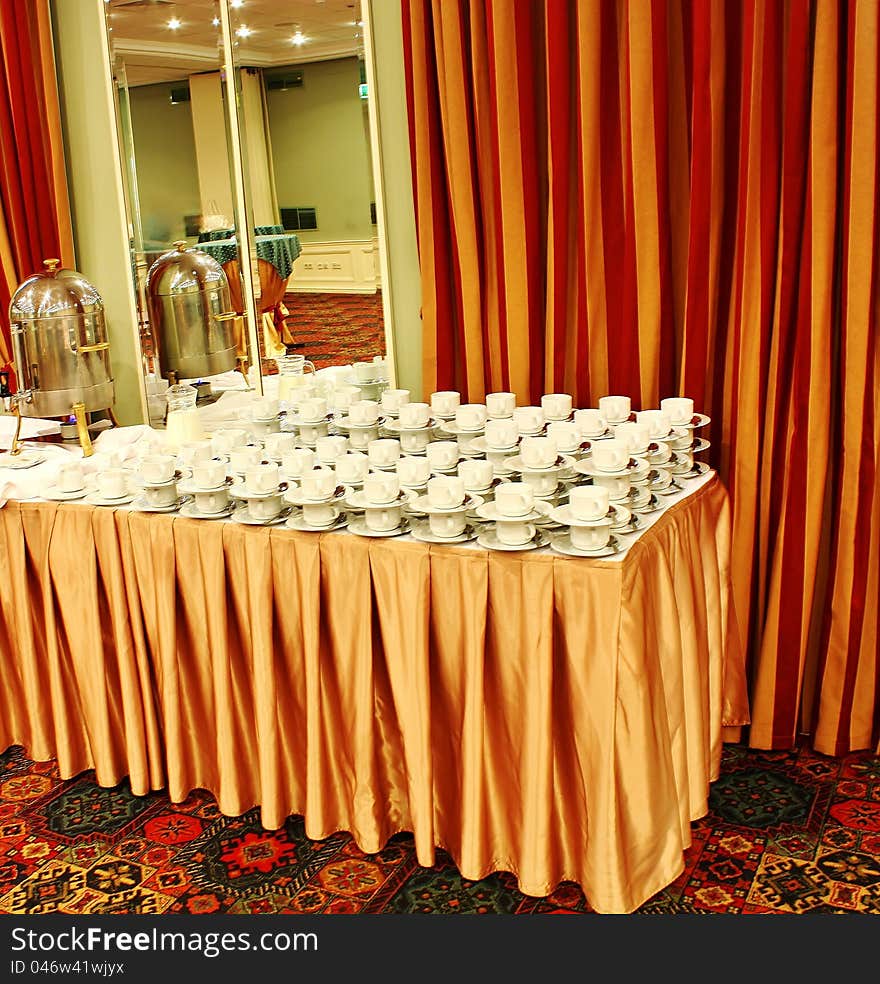 Boiler and  tea cups on the table in the hall of the conference center. Boiler and  tea cups on the table in the hall of the conference center