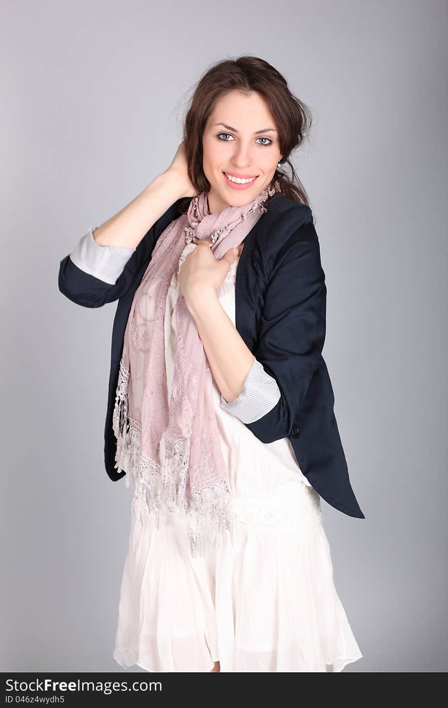 Beautiful smiling girl in a blue coat over gray background. Studio shot.