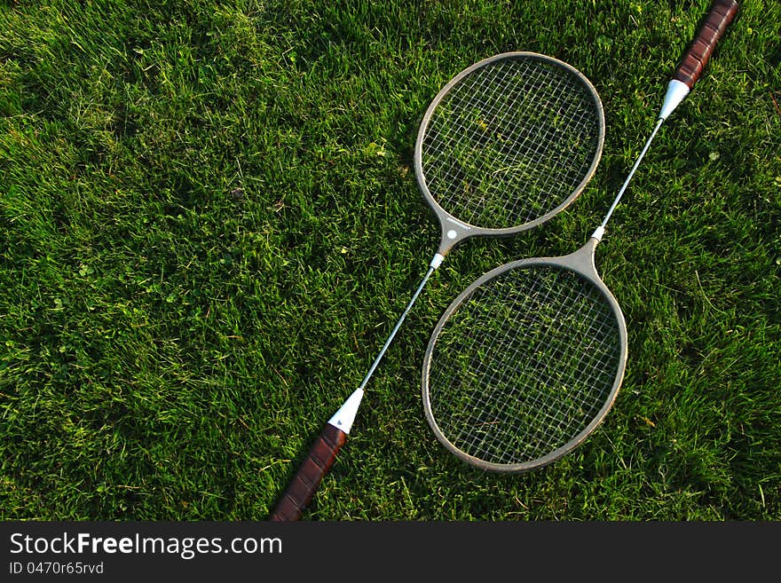 Badminton rackets resting upon green grass. Badminton rackets resting upon green grass