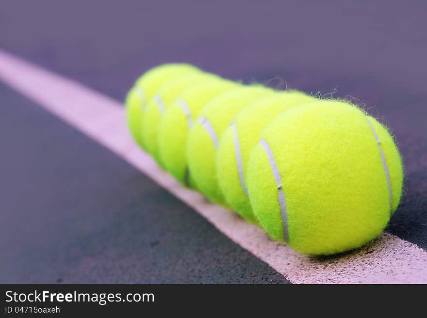 Tennis balls close up arranged in row on hard court synthetic tennis turf. Tennis balls close up arranged in row on hard court synthetic tennis turf