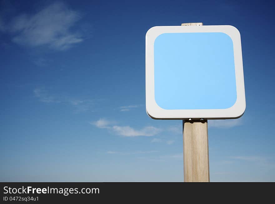 Foreground of a square white  sign with blue sky. Foreground of a square white  sign with blue sky