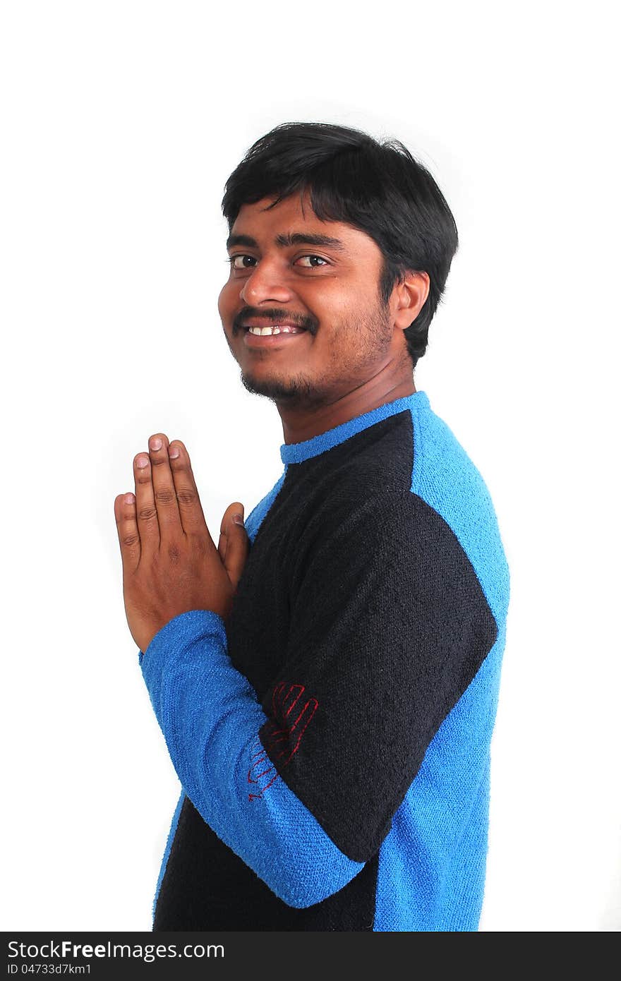 Young guy in praying stance but relaxed and smiling