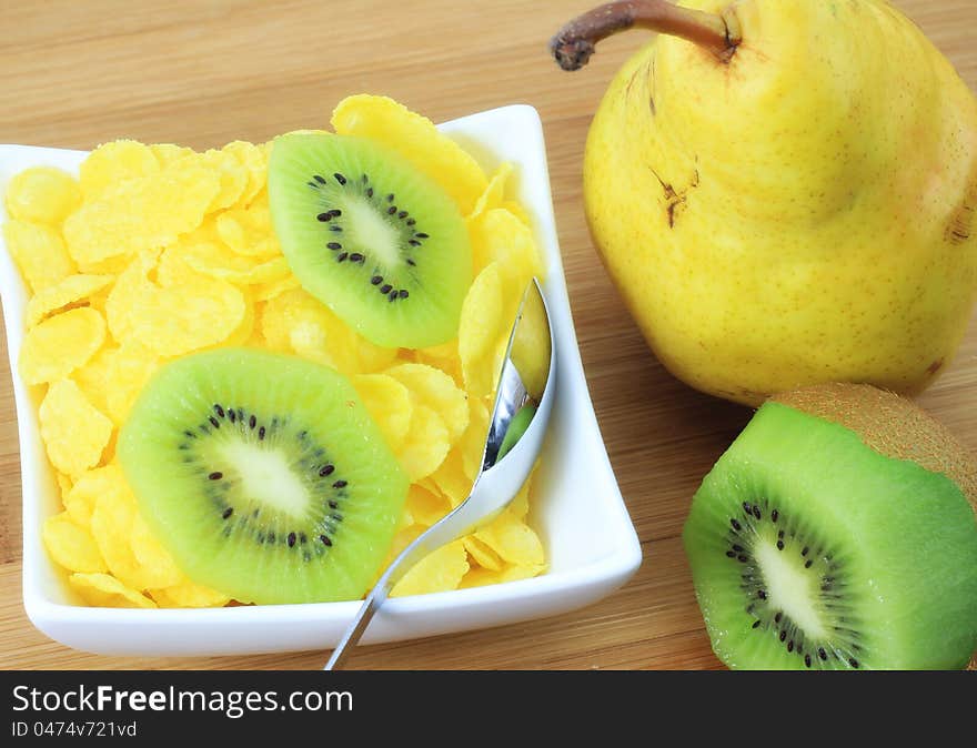 A concept of healthy and light meal; corn flakes, pear and kiwi on the table. A concept of healthy and light meal; corn flakes, pear and kiwi on the table.