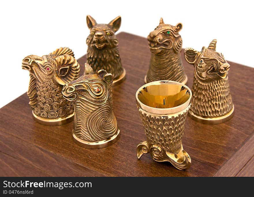 Golden animal-shaped glasses for strong spirits on the wooden box. Golden animal-shaped glasses for strong spirits on the wooden box