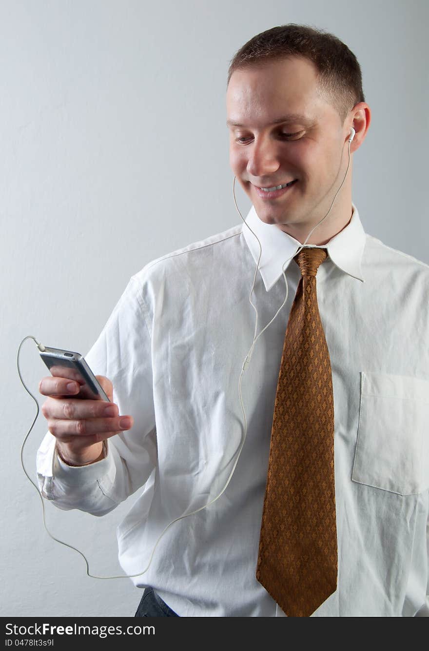 Young smiling businessman listening to music through the headset.