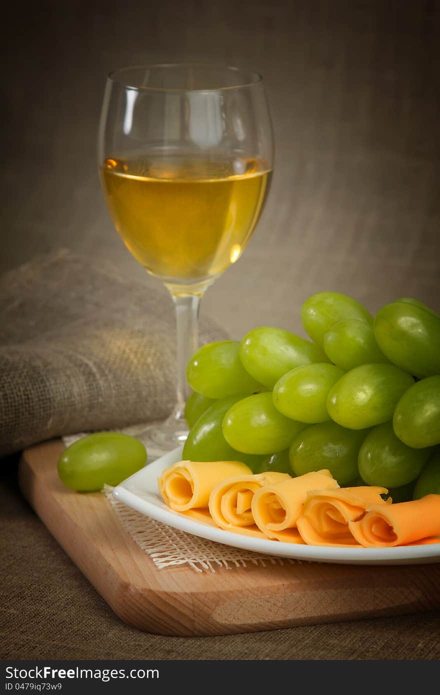 A glass of white wine, green grapes of wine on a wooden surface. A glass of white wine, green grapes of wine on a wooden surface