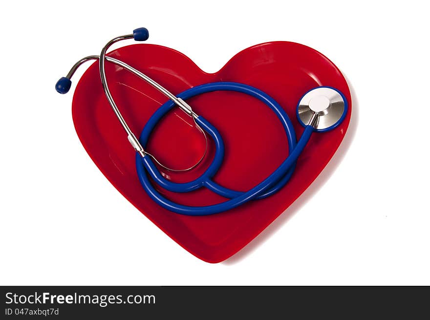 Nice blue stethoscope laying in a red heart-shaped plate.  Isolated on white. Has shadow on the right side. Nice blue stethoscope laying in a red heart-shaped plate.  Isolated on white. Has shadow on the right side.