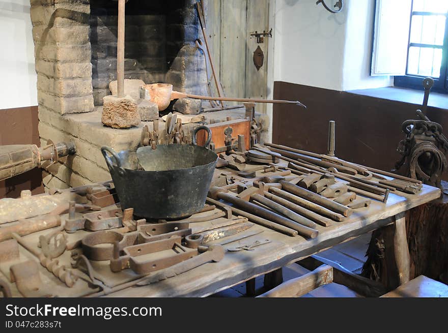 Looking at the tools of a blacksmith shop with tools on the table, lit by sunshine coming in to the window. Looking at the tools of a blacksmith shop with tools on the table, lit by sunshine coming in to the window