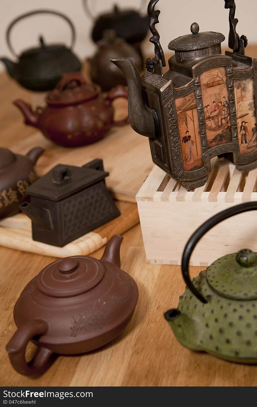 A collection of Japanese and Chinese teapots on a wooden table. A collection of Japanese and Chinese teapots on a wooden table