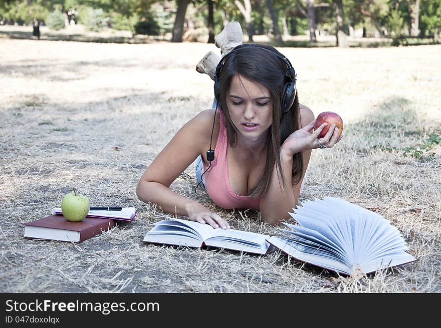 Young woman lying on the grass and holding a apple photographed in  park. Young woman lying on the grass and holding a apple photographed in  park