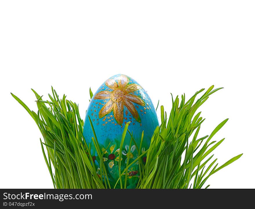 Ornated blue easter egg between green grass isolated on white background. Ornated blue easter egg between green grass isolated on white background