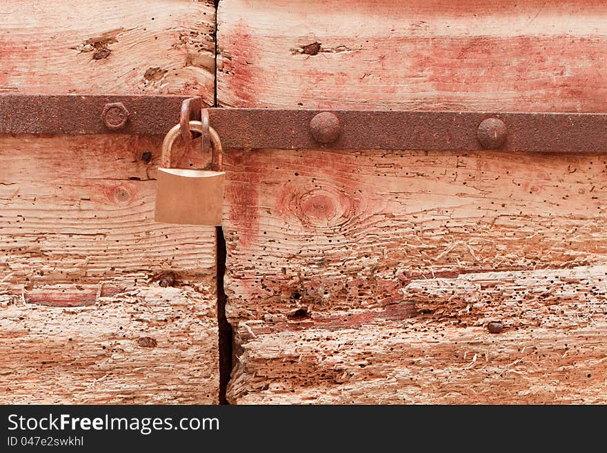 Closed padlock on a woodworm eaten door. Closed padlock on a woodworm eaten door