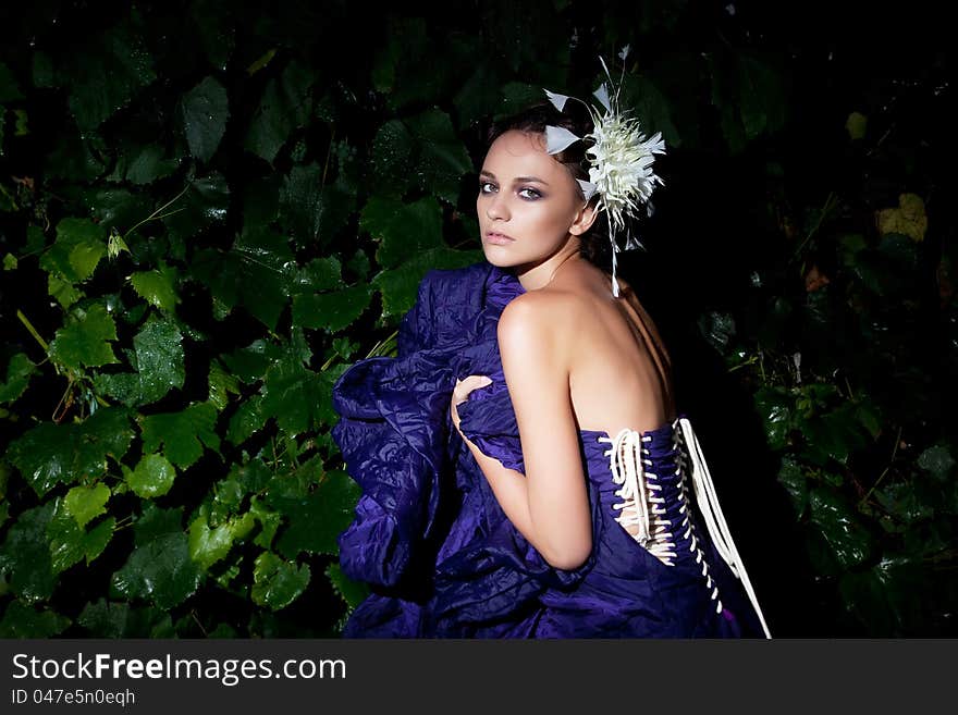 Nocturnal scenery - fashionable woman in blue dress among green plants. Nocturnal scenery - fashionable woman in blue dress among green plants