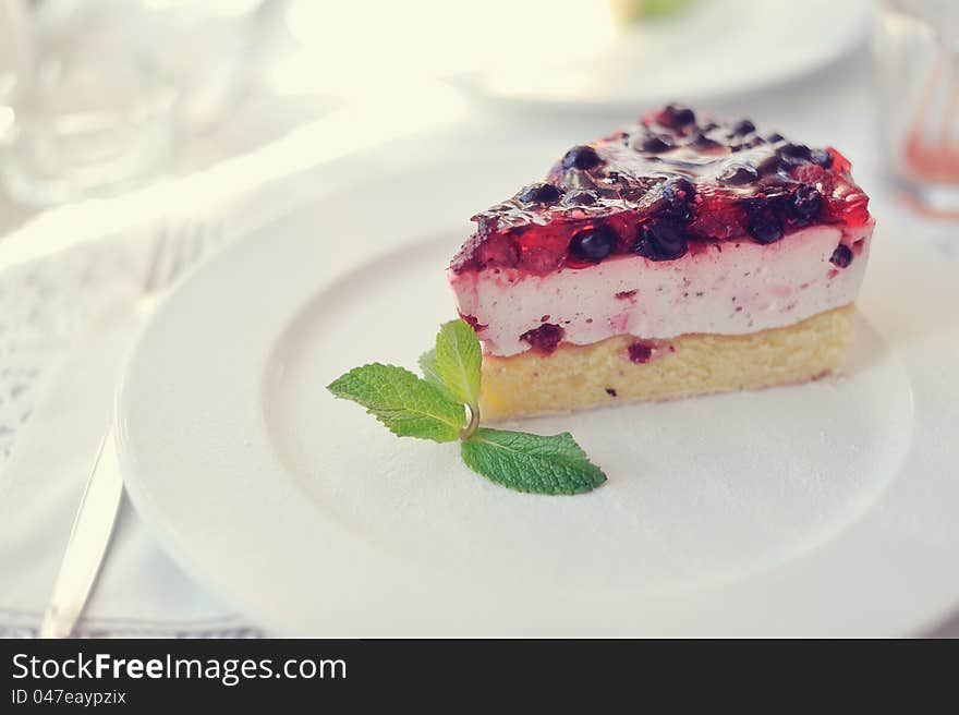 On a white plate an appetizing cake with a mint leaf. On a white plate an appetizing cake with a mint leaf