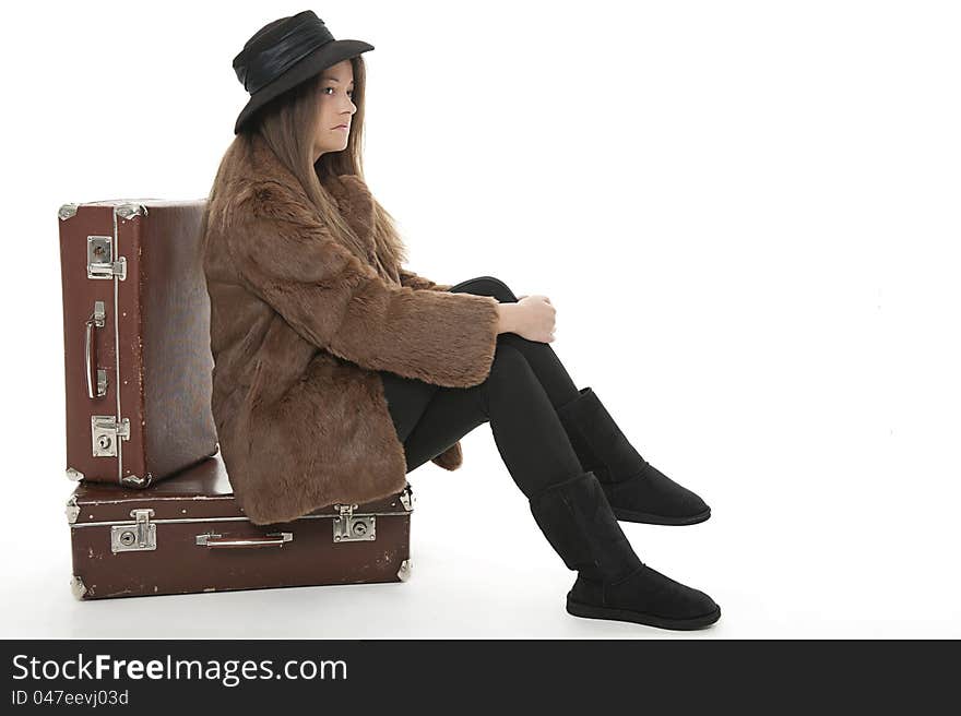 Young woman is sitting on the luggage, studio shot. Young woman is sitting on the luggage, studio shot