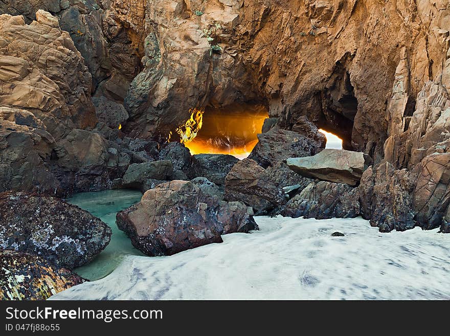 Sunsetting light coming through of small opening and interesting rock formation along the Pacific ocean coastline. Sunsetting light coming through of small opening and interesting rock formation along the Pacific ocean coastline.