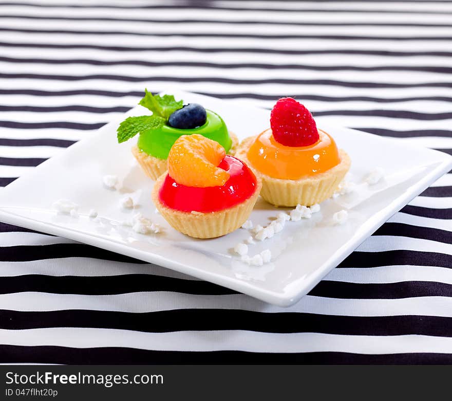 Sweet snack jelly raspberry blueberry and orange cupcake display on dish. Sweet snack jelly raspberry blueberry and orange cupcake display on dish