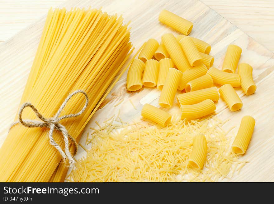 Different types of raw pasta, noodle, spaghetti, tortiglioni on wooden table. Different types of raw pasta, noodle, spaghetti, tortiglioni on wooden table