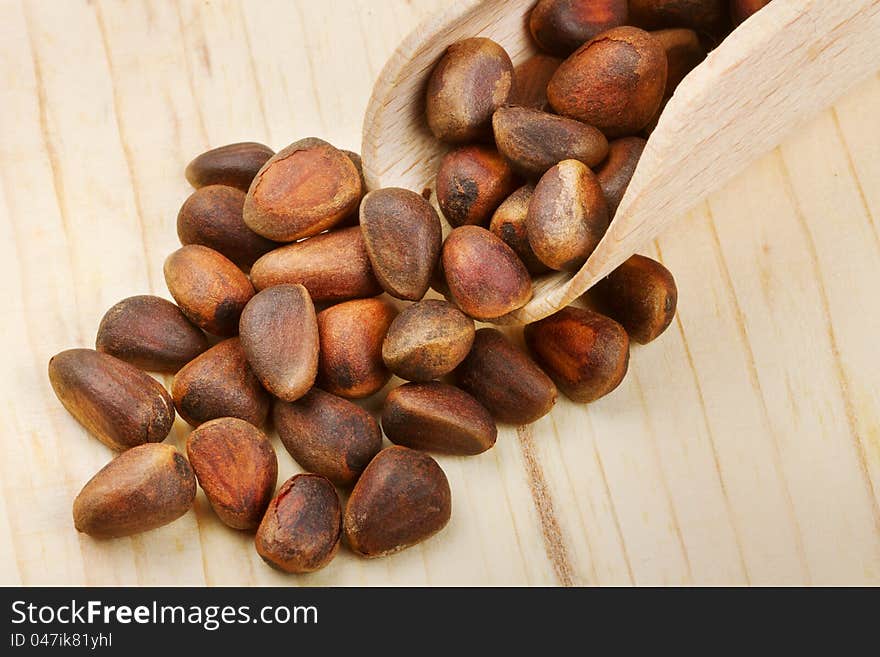 Wooden scoop with pine nuts on table