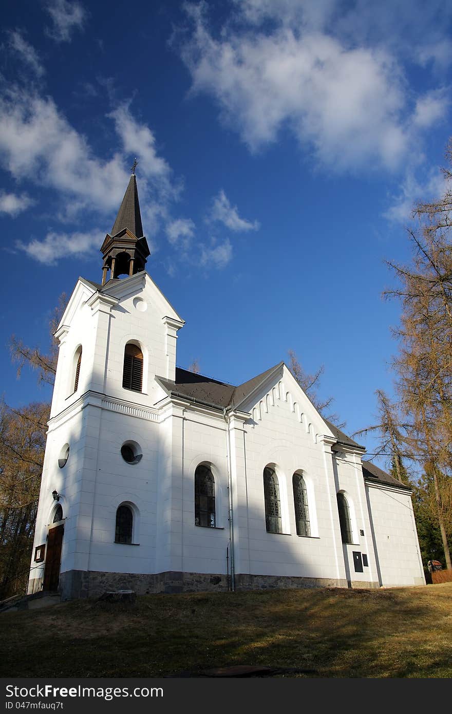 Small white catholic church with blue sky and white clouds. Small white catholic church with blue sky and white clouds