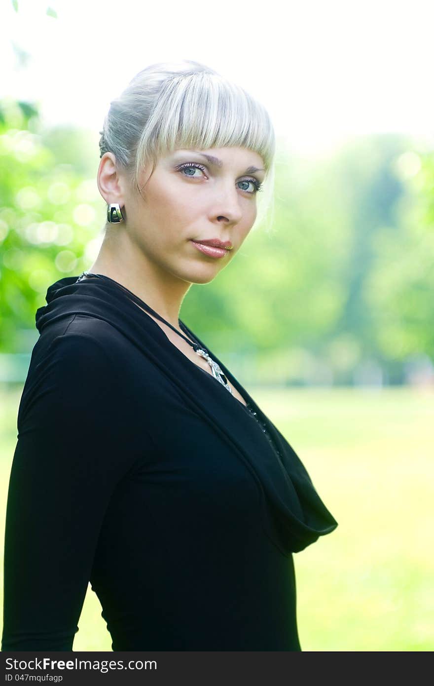 Beautiful young woman in black dress on green background