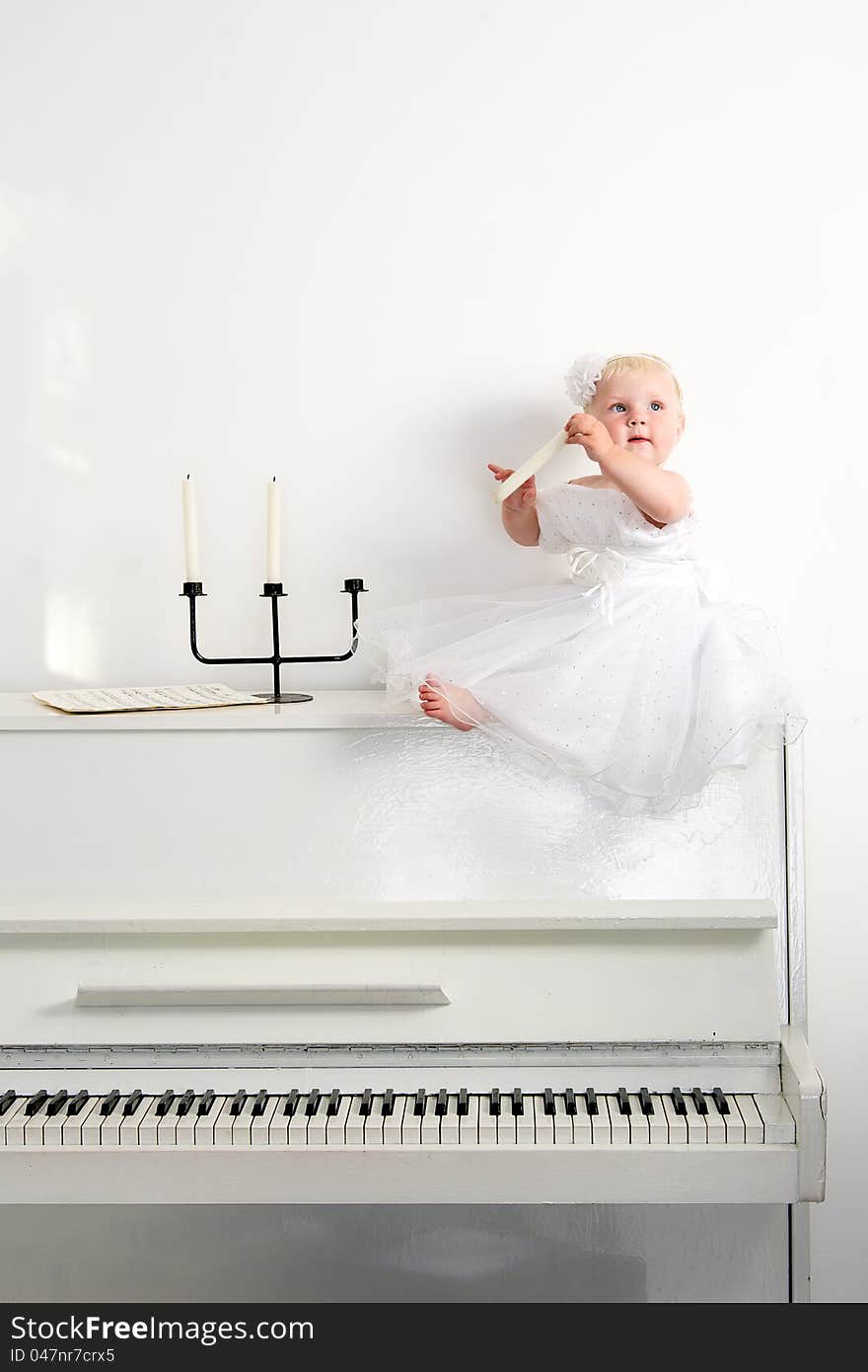 A girl in white dress sitting on a piano in the room. A girl in white dress sitting on a piano in the room