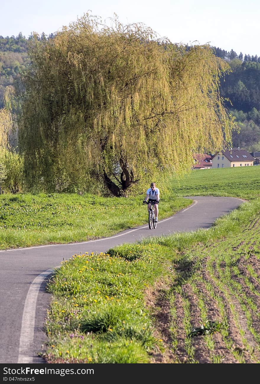 Cyclist cycling on a cycle path in fields in spring. Cyclist cycling on a cycle path in fields in spring.