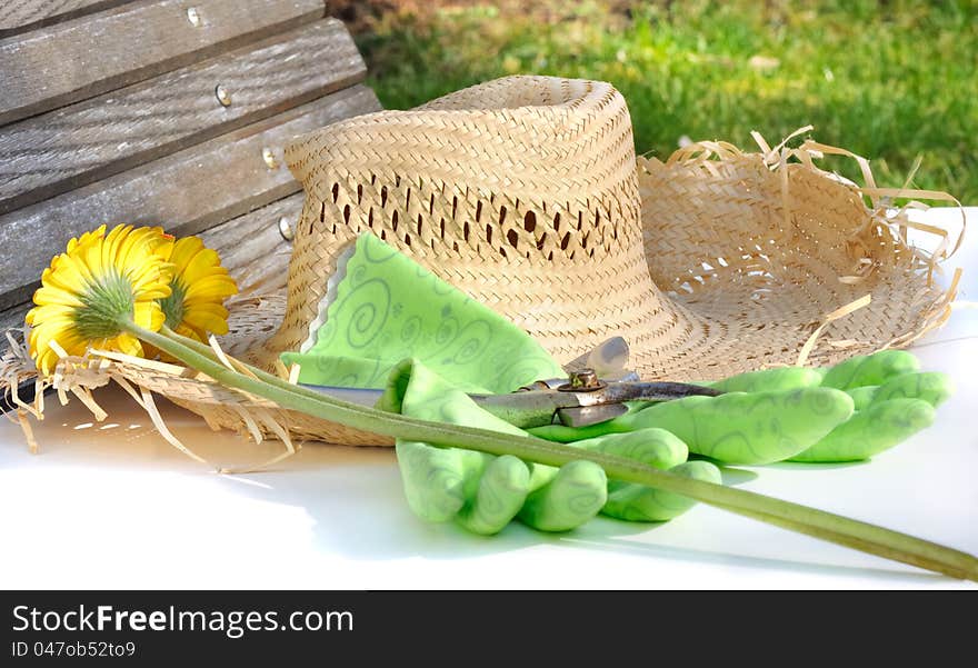 Straw hat next to gloves and pruners and cut flowers in a garden. Straw hat next to gloves and pruners and cut flowers in a garden